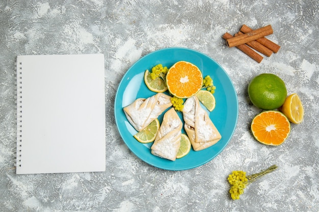 Vista superior deliciosos pasteles de masa con rodajas de limón sobre el fondo blanco pastelería azúcar hornear masa de pastel galleta dulce