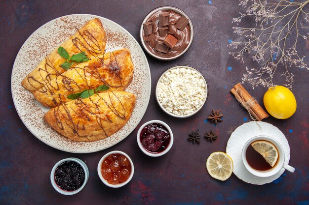 Vista superior deliciosos pasteles con mermelada y requesón sobre fondo morado oscuro pastelería dulce hornear té pastel galleta de azúcar