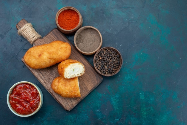 Vista superior deliciosos pasteles con relleno de carne y condimentos en el fondo azul oscuro pastel de masa pan bollo hornear alimentos