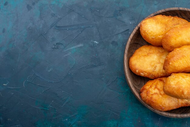 Vista superior deliciosos pasteles con relleno de carne en el escritorio azul oscuro pastel de masa pan bollo comida