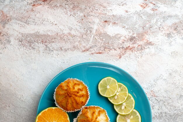 Vista superior de deliciosos pasteles con rodajas de limón dentro de la placa sobre fondo blanco pastel de cítricos de frutas para hornear galletas de masa de azúcar