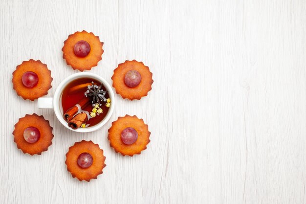 Foto gratuita vista superior deliciosos pasteles con taza de té en la superficie blanca postre galleta pastel de té pastel de galleta