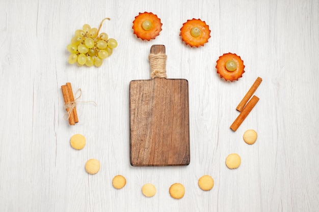 Foto gratuita vista superior de deliciosos pasteles con uvas y galletas en el escritorio blanco pastel de frutas galletas postre dulce té