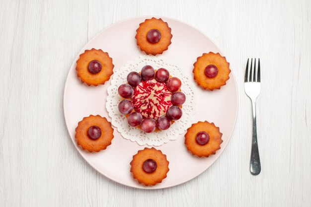 Vista superior de deliciosos pasteles con uvas en el postre de tarta de galletas de mesa blanca