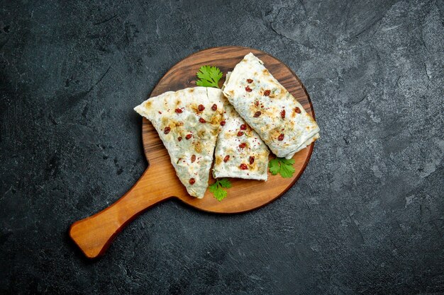 Vista superior deliciosos qutabs enrollados en rodajas de masa rellenas de verde en el espacio gris