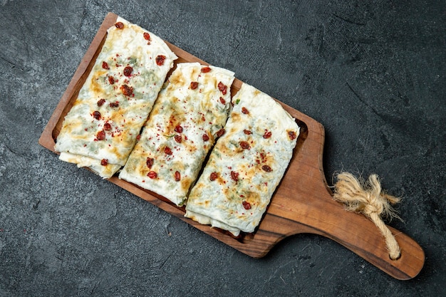 Vista superior deliciosos qutabs enrollados en rodajas de masa rellenas de verde en el espacio gris