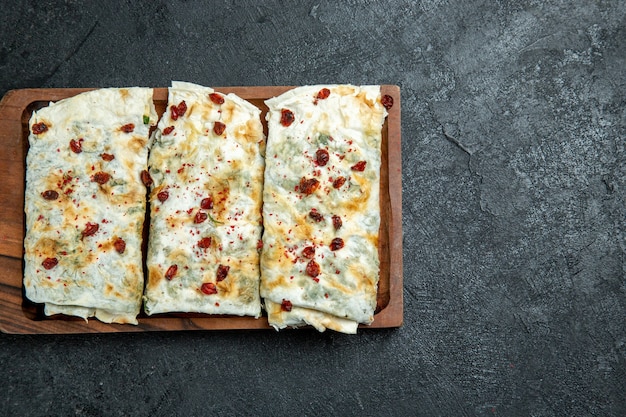 Vista superior deliciosos qutabs enrollados en rodajas de masa rellenas de verde en el espacio gris