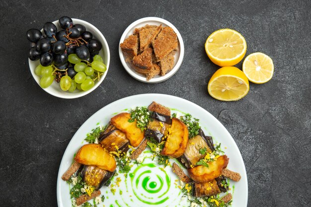 Vista superior deliciosos rollos de berenjena con patatas al horno dentro de la placa en el fondo oscuro plato comida cena comida patata vegetal