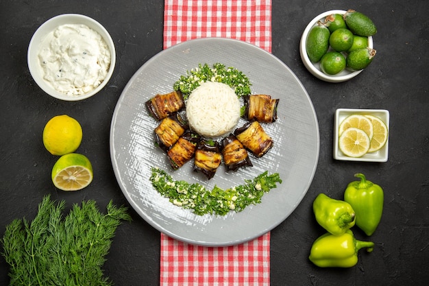 Vista superior deliciosos rollos de berenjena plato cocido con arroz en un escritorio oscuro cocina de aceite de planta de arroz cocina alimentaria