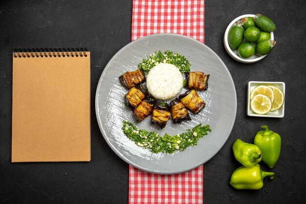 Vista superior deliciosos rollos de berenjena plato cocido con arroz en la superficie oscura cocina de aceite vegetal de arroz