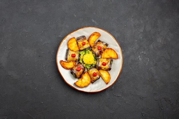 Vista superior deliciosos rollos de berenjena plato cocido con papas al horno en el plato de comida de fondo oscuro cocinar alimentos hornear papas fritas