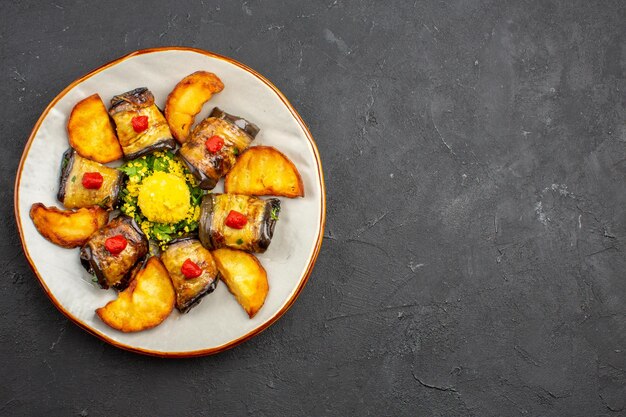 Vista superior deliciosos rollos de berenjena plato cocido con papas al horno en el plato de comida de fondo oscuro cocinar alimentos hornear papas fritas