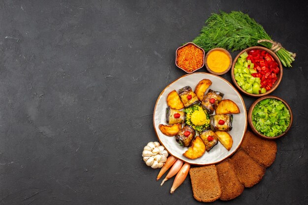 Vista superior deliciosos rollos de berenjena plato cocido con papas y hogazas de pan en el fondo oscuro cocinar alimentos freír plato hornear papa