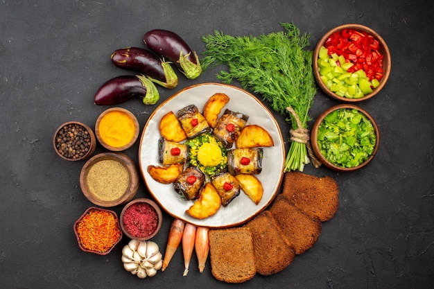 Vista superior deliciosos rollos de berenjena plato cocido con papas y hogazas de pan sobre fondo oscuro cocinar alimentos papas fritas plato hornear