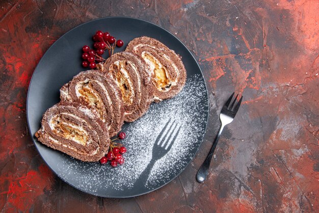 Vista superior de deliciosos rollos de galletas con frutas en el piso oscuro