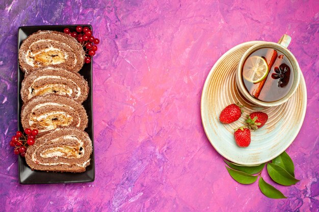 Vista superior de deliciosos rollos de galletas con taza de té en el escritorio rosa