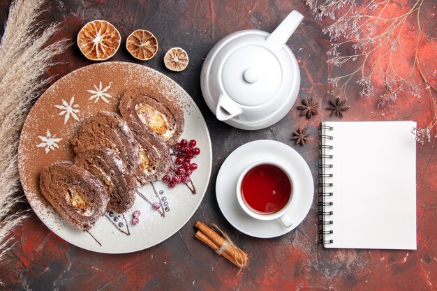 Vista superior de deliciosos rollos de galletas con una taza de té en la mesa oscura