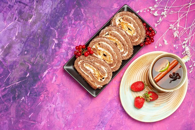 Vista superior de deliciosos rollos de galletas con taza de té sobre fondo rosa