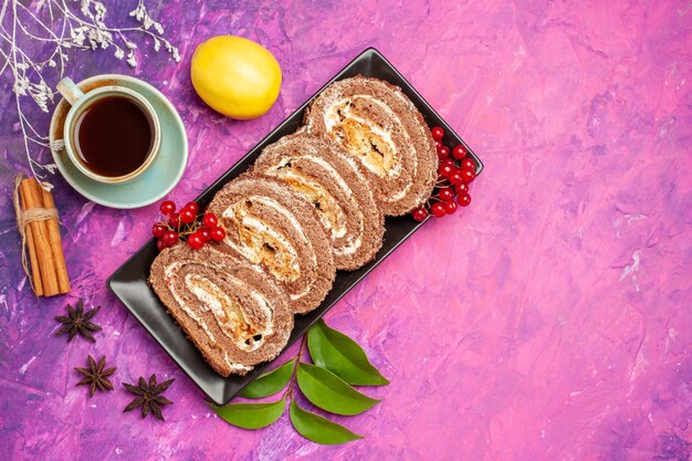 Vista superior de deliciosos rollos de galletas con taza de té sobre fondo rosa