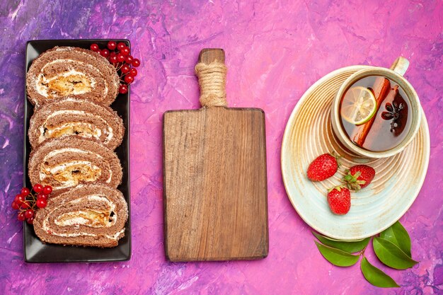 Vista superior de deliciosos rollos de galletas con taza de té sobre fondo rosa