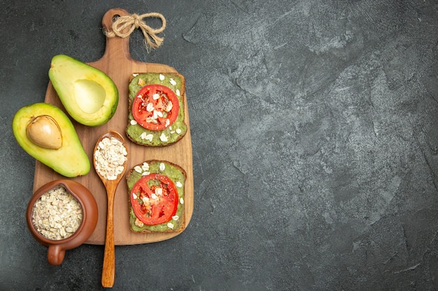 Vista superior deliciosos sándwiches con aguacate y tomates rojos en el sándwich de hamburguesa de comida de merienda de fondo gris