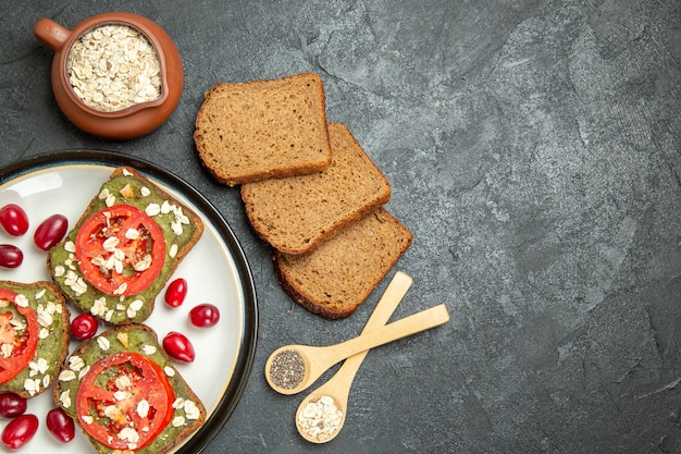 Vista superior deliciosos sándwiches con pasta de aguacate y tomates dentro de la placa sobre el fondo gris pan sándwich de hamburguesa