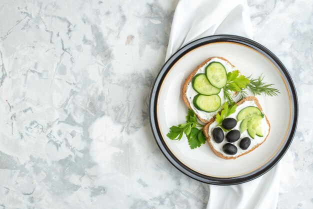 Vista superior deliciosos sándwiches con pepinos y aceitunas dentro del plato fondo blanco salud comida horizontal pan almuerzo tostadas hamburguesa