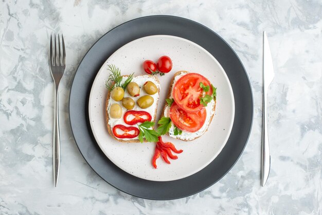 Vista superior deliciosos sándwiches con tomates y aceitunas dentro de la placa fondo blanco pan comida almuerzo comida tostadas hamburguesa sándwich horizontal