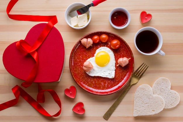 Vista superior del desayuno romántico con café y huevo en forma de corazón.
