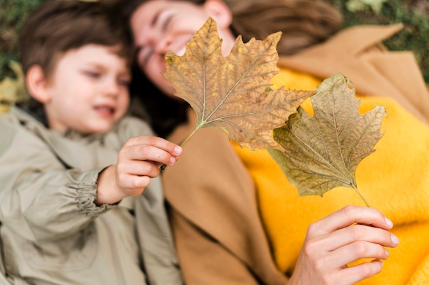 Vista superior desenfocado niño y madre jugando con hojas de otoño