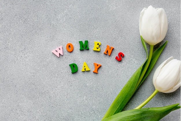 Foto gratuita vista superior del día de la mujer letras sobre cemento con tulipanes blancos