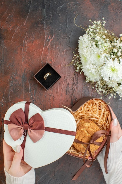 Vista superior del día de san valentín presente pequeña galleta con flores sobre un fondo oscuro amor color sentimiento matrimonio vacaciones pareja regalo