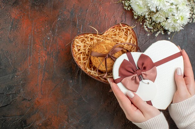 Vista superior día de san valentín presente pequeñas galletas con flores en el fondo marrón oscuro amor color regalo sentimiento matrimonio vacaciones pareja