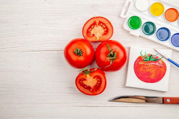 Vista superior dibujo de tomate pequeño con tomates frescos en el escritorio blanco