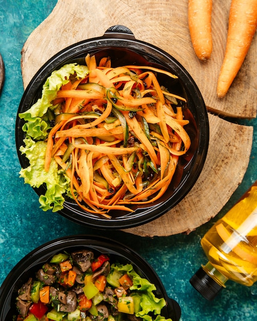 Vista superior dieta zanahoria y ensalada de pepino con lechuga en el tablero