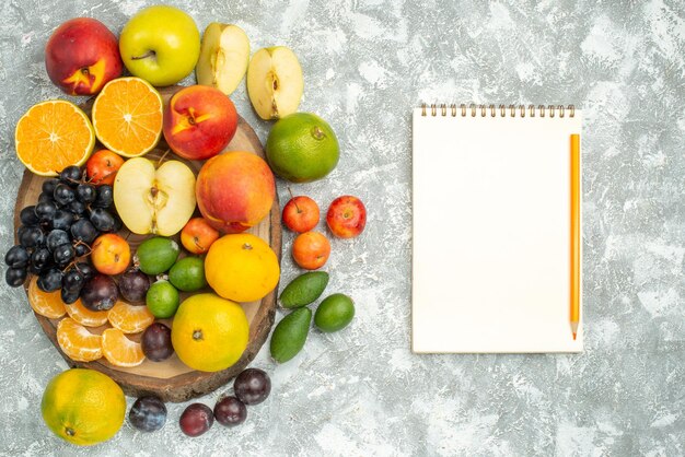 Vista superior diferente composición de frutas en rodajas y frutas frescas enteras sobre fondo blanco árbol vitamina frutas maduras color suave