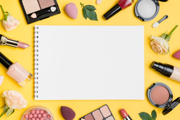 Vista superior de diferentes arreglos de productos de belleza con libreta vacía