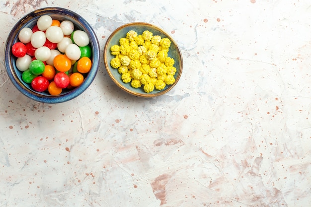 Foto gratuita vista superior de diferentes caramelos dulces con confituras en la mesa blanca color caramelo dulce