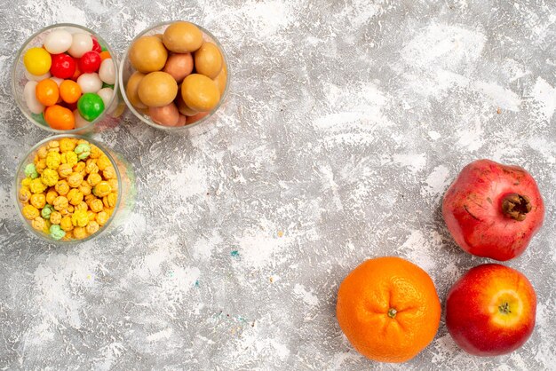 Vista superior de diferentes caramelos dulces con frutas sobre superficie blanca