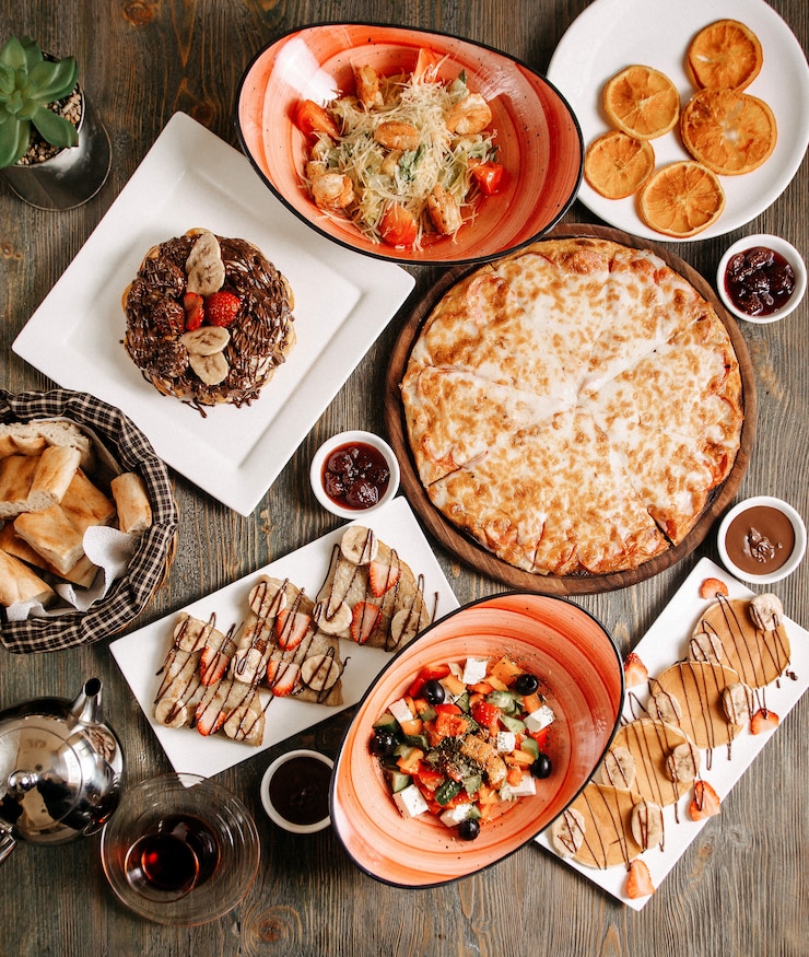 Foto gratuito vista superior de diferentes comidas, como pizza, vegetales, ensalada de grecia, panqueques y otros en el piso claro