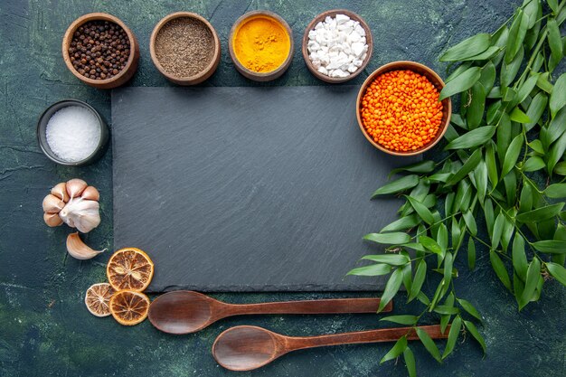 Vista superior de diferentes condimentos con ajo y lentejas naranjas sobre fondo azul oscuro Foto comida picante pimiento picante color sopa de semillas afiladas