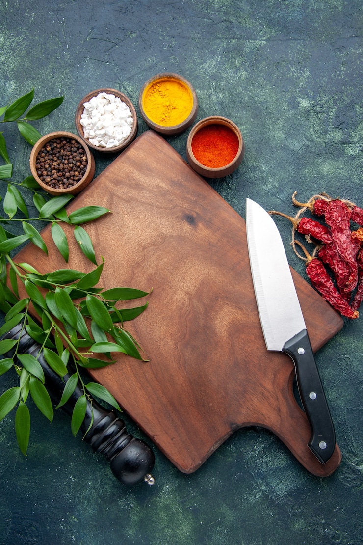 Foto gratuito vista superior de diferentes condimentos con escritorio de madera marrón en la superficie de color azul oscuro cubiertos de madera afilados árbol verde cocina