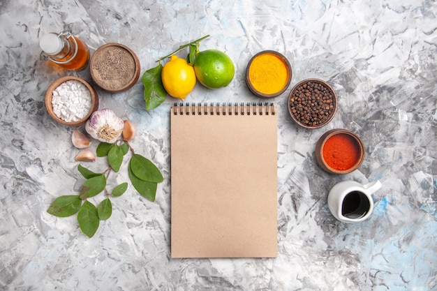 Foto gratuita vista superior de diferentes condimentos con limón y ajo en aceite de mesa blanco sal de fruta picante