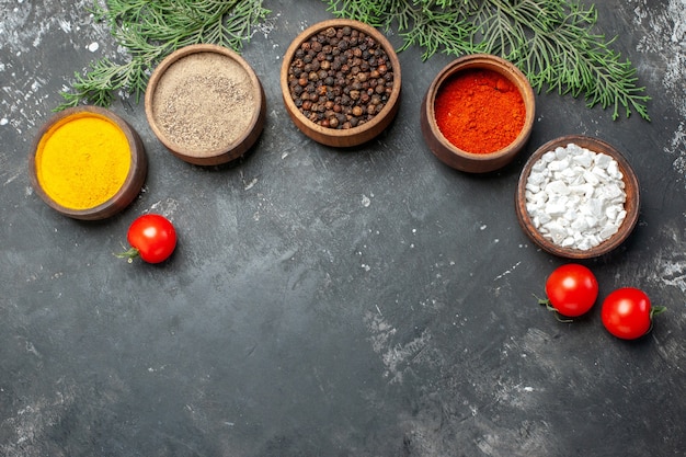 Vista superior de diferentes condimentos con tomates sobre fondo gris