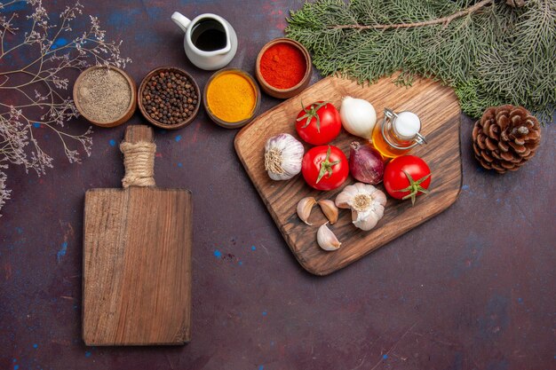 Vista superior de diferentes condimentos con verduras frescas en mesa negra