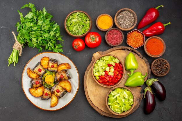 Vista superior de diferentes condimentos con verduras frescas en mesa negra