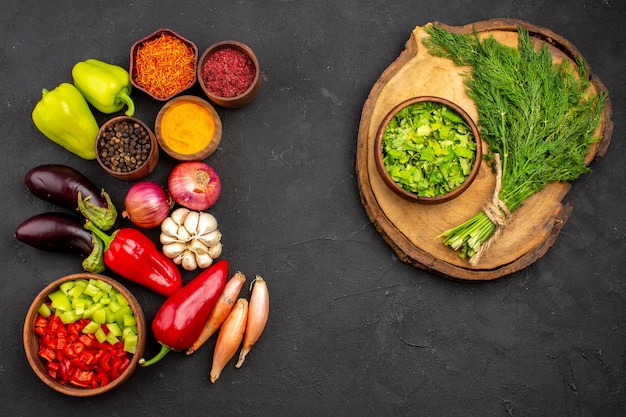 Vista superior de diferentes condimentos con verduras frescas y verduras sobre fondo oscuro ensalada de verduras de comida madura