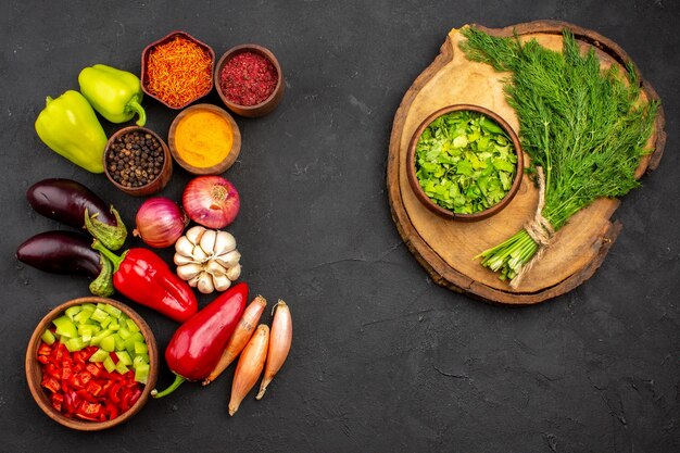 Vista superior de diferentes condimentos con verduras frescas y verduras sobre fondo oscuro ensalada de verduras de comida madura