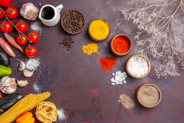 Vista superior de diferentes condimentos con verduras sobre fondo oscuro, sopa, salsa, comida, pimiento picante.