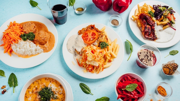 Vista superior de diferentes deliciosas ensaladas con sopas de crema y papas fritas en la mesa